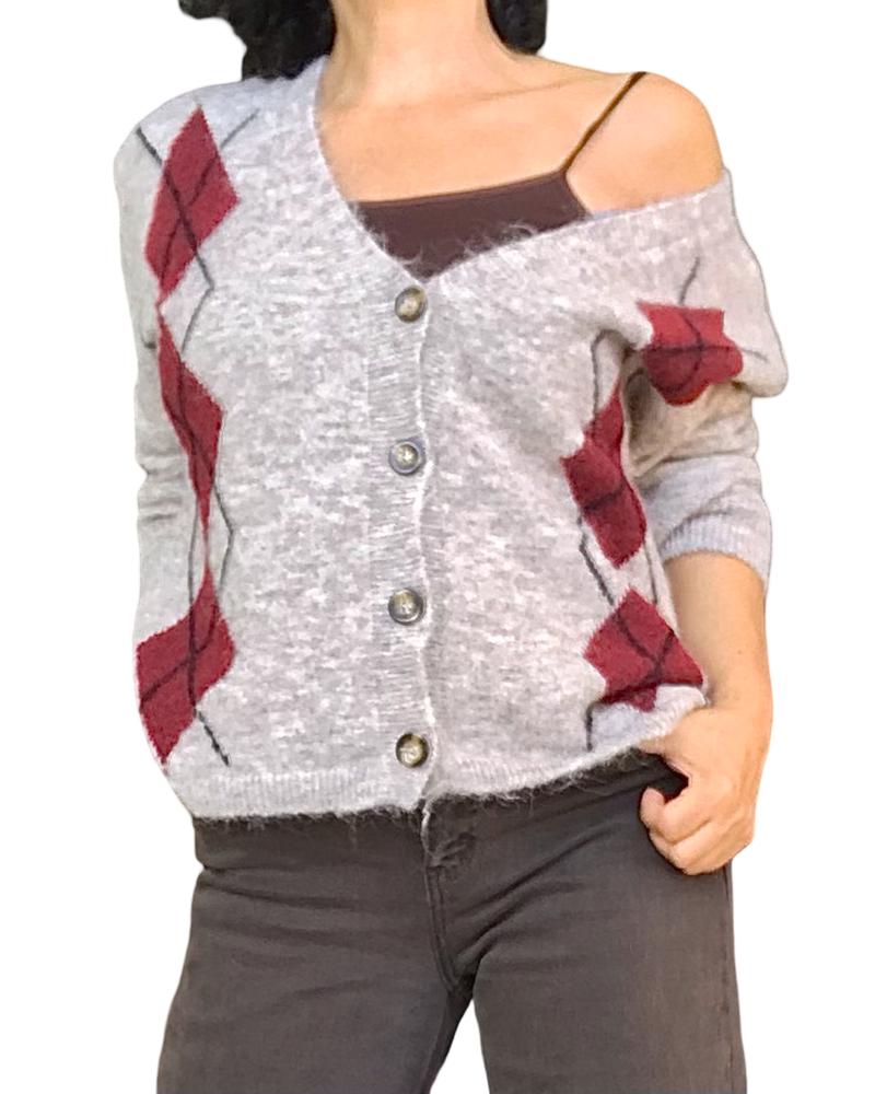 Cardigan en tricot beige à losanges bourgogne porté sur un haut brun, glissé sur l’épaule