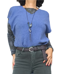 Débardeur en tricot bleu jeans col V porté en superposition sur un haut imprimé, avec long collier et ceinture tressée