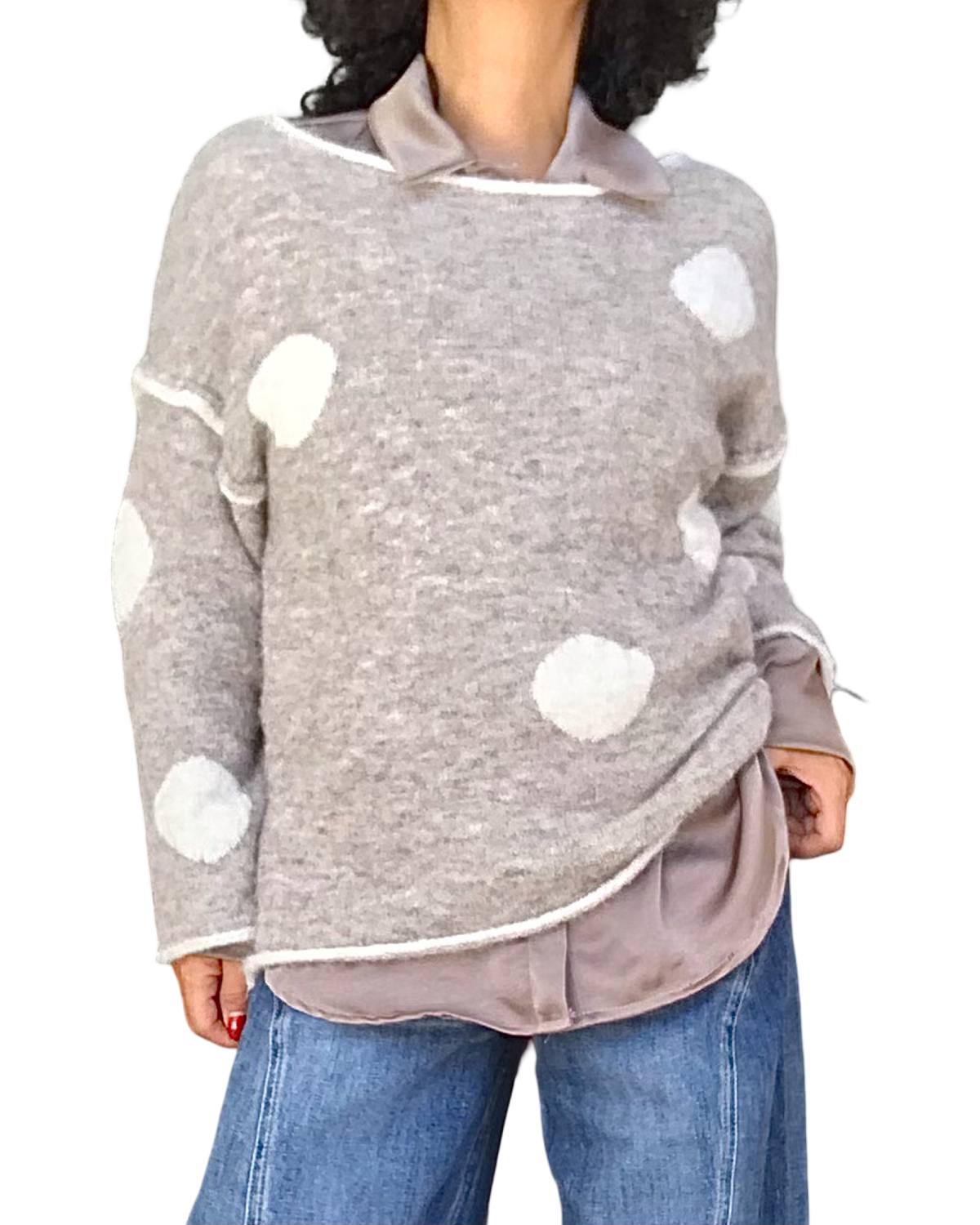 Chandail beige chiné à grosses pastilles blanches texturées porté sur une chemise en satin avec jeans