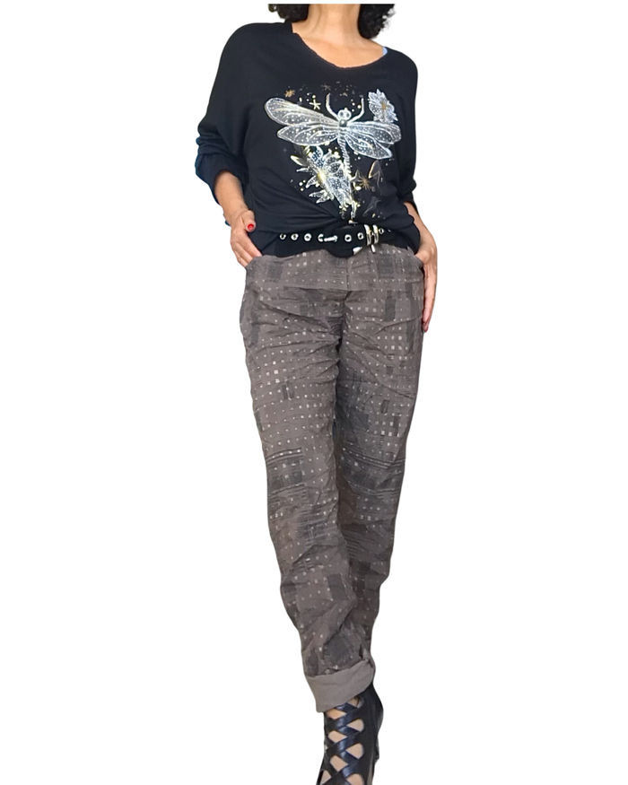 Tenue : chandail uni noir col en V avec une libellule moka dorée et argentée et pantalon brun à taille élastique avec cordon, imprimé d’un léger motif noir et petits carreaux dorés