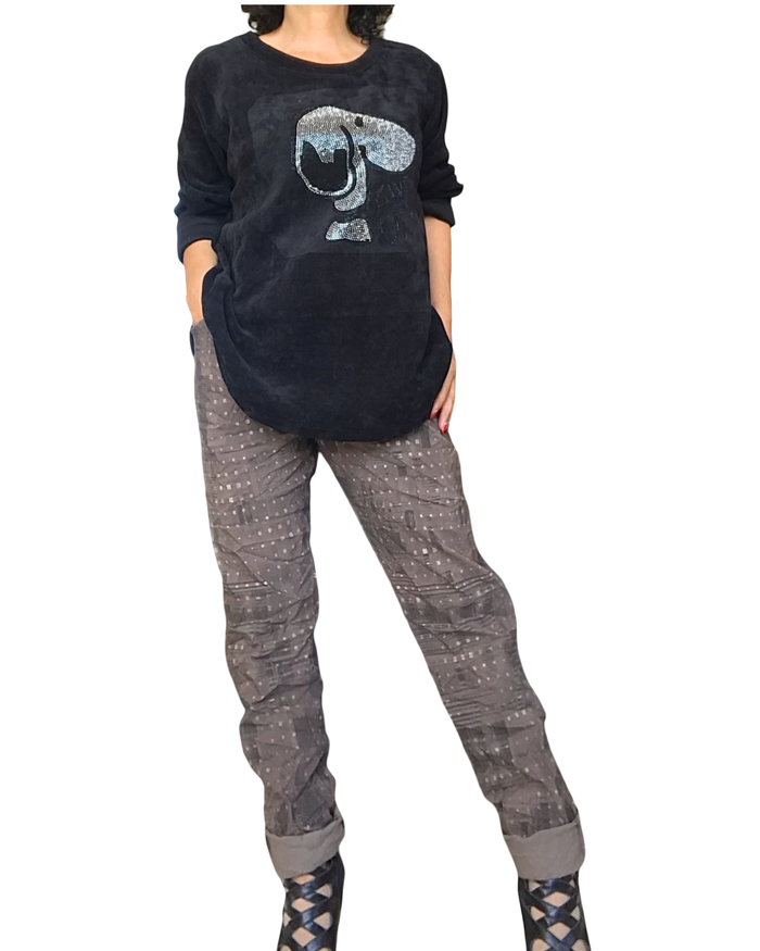 Tenue : chandail uni noir col rond avec Snoopy argenté et pantalon brun à taille élastique avec cordon, imprimé d’un léger motif noir et petits carreaux dorés